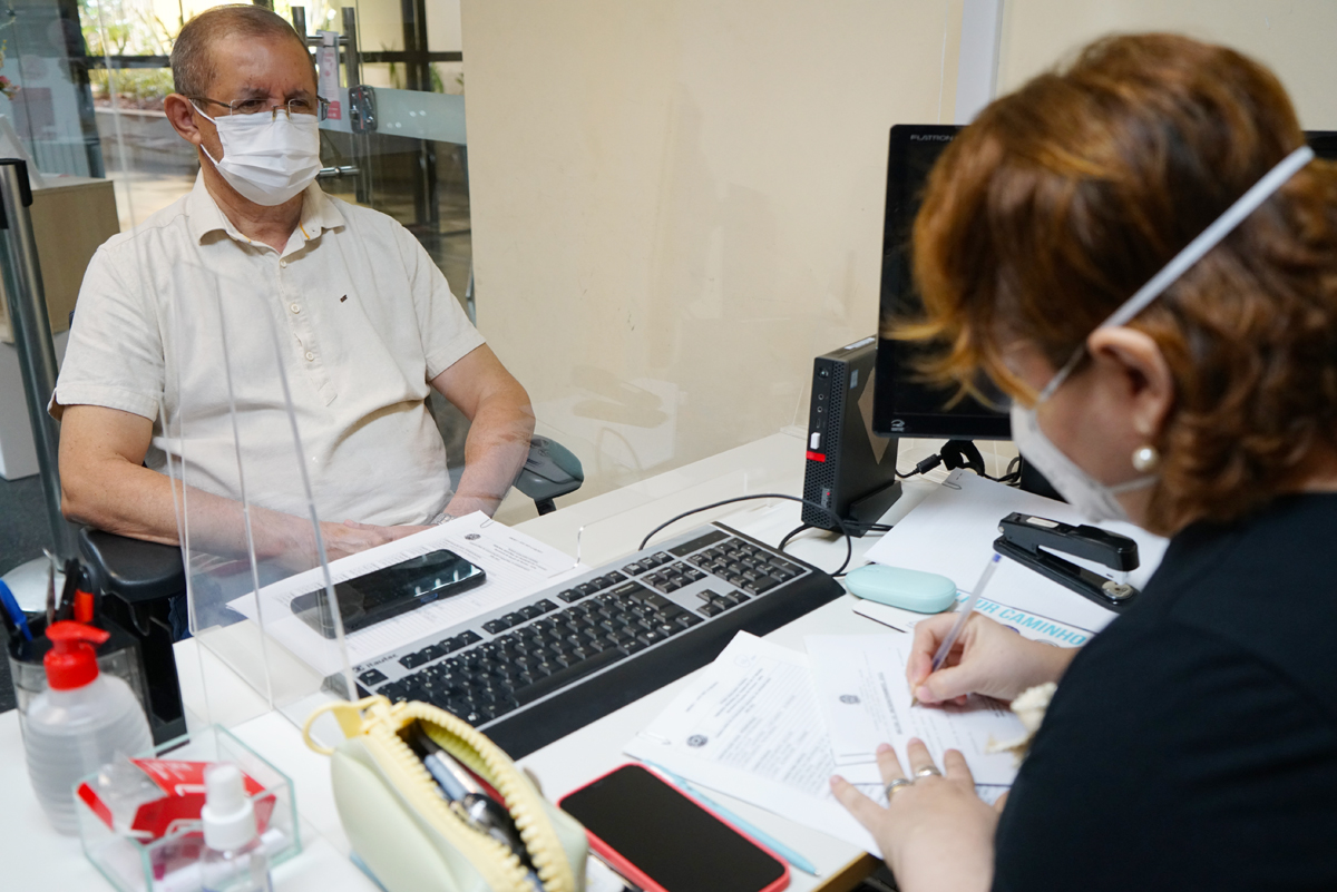 Servidor aposentado sendo atendido no balcão do recadastramento