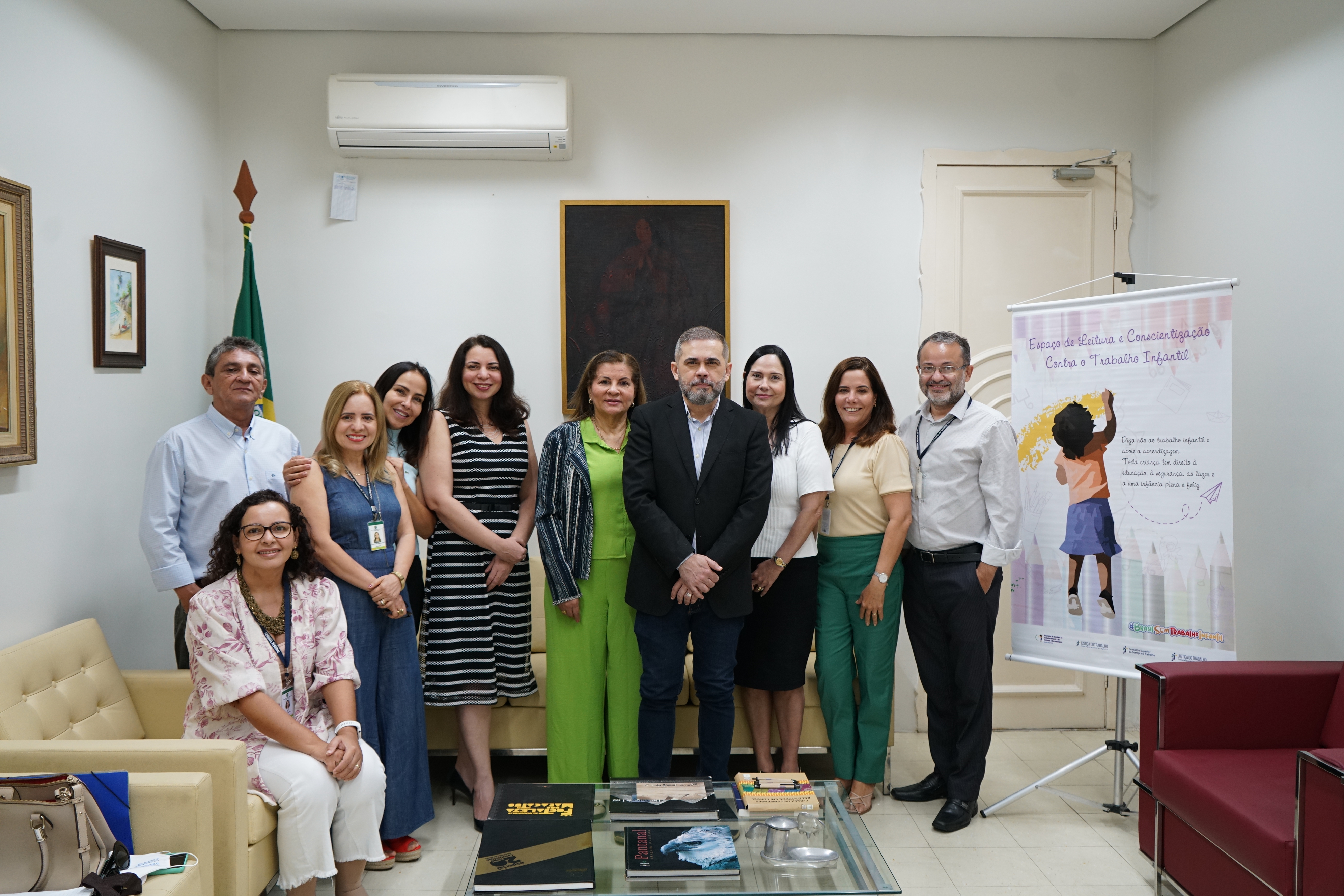 Foto da comissão de combate ao trabalho infantil. Estão todos juntos, sorridentes, numa foto posada e ao lado tem um banner do Programa. No grupo, estão os gestores regionais e a comissão de apoio, além de convidados. Há 7 mulheres e 3 homens.