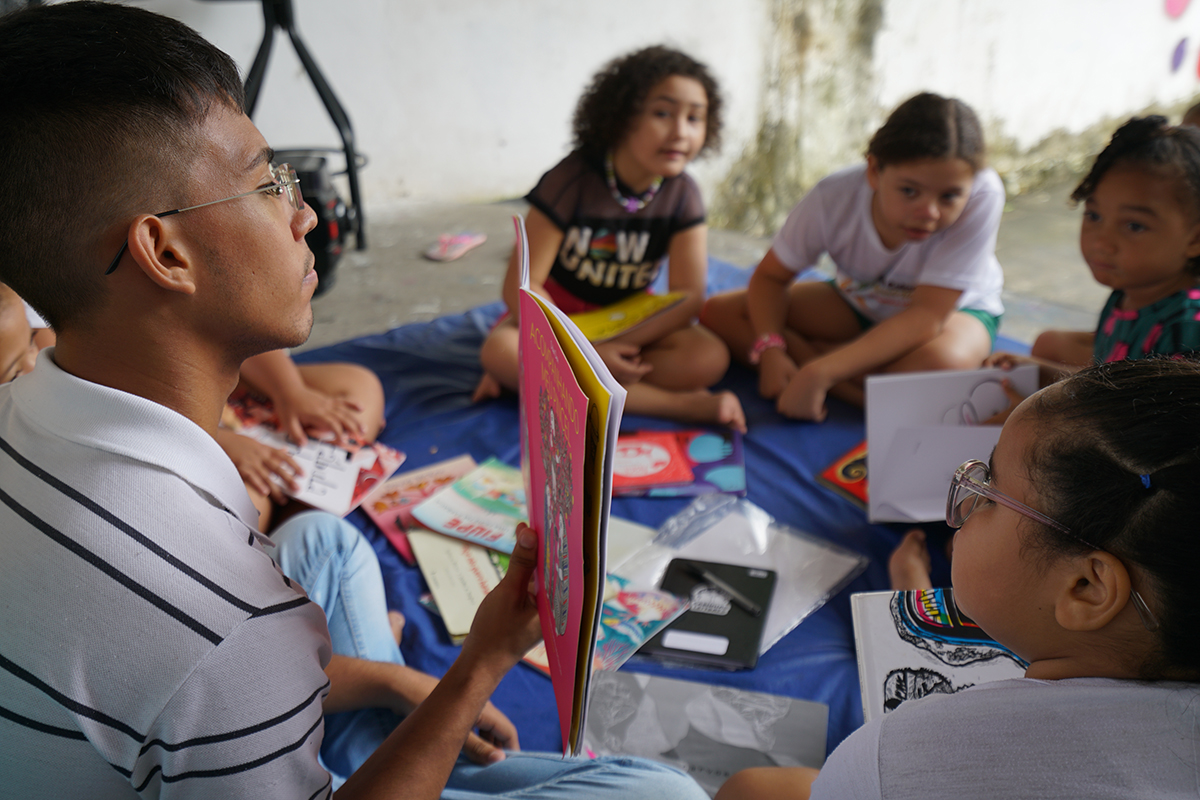 Jovem realiza leitura para crianças em uma roda