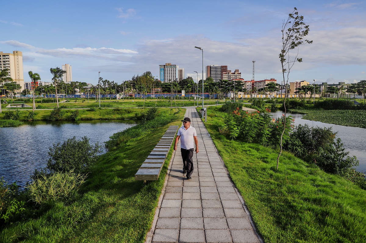 homem caminha numa praça verde