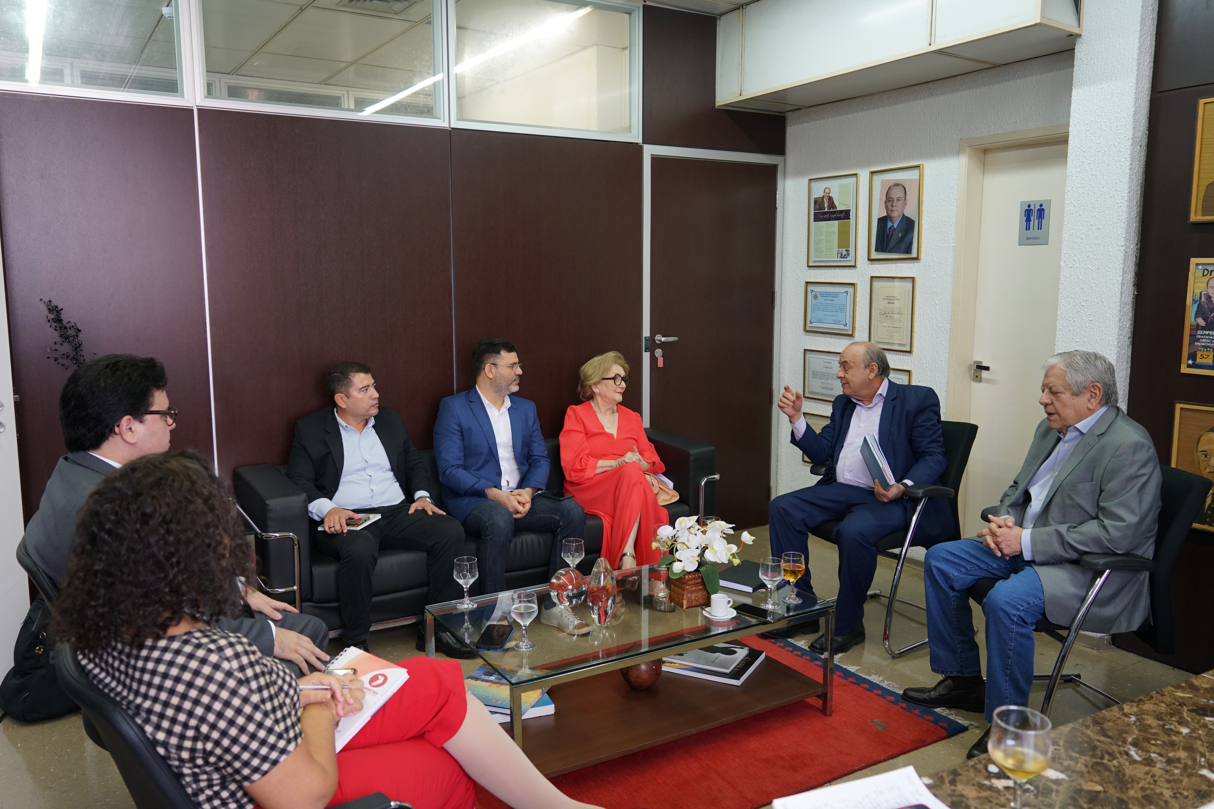 Foto em que há um grupo de 7 pessoas sentadas. Há duas mulheres e 5 homens. No momento, o des. Antônio Parente está falando e gesticulando e todos estão olhando para ele.