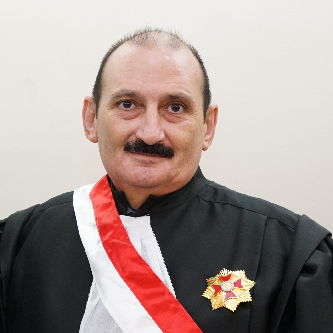 Homem branco calvo e de bigode, de toga preta e faixa de desembargador