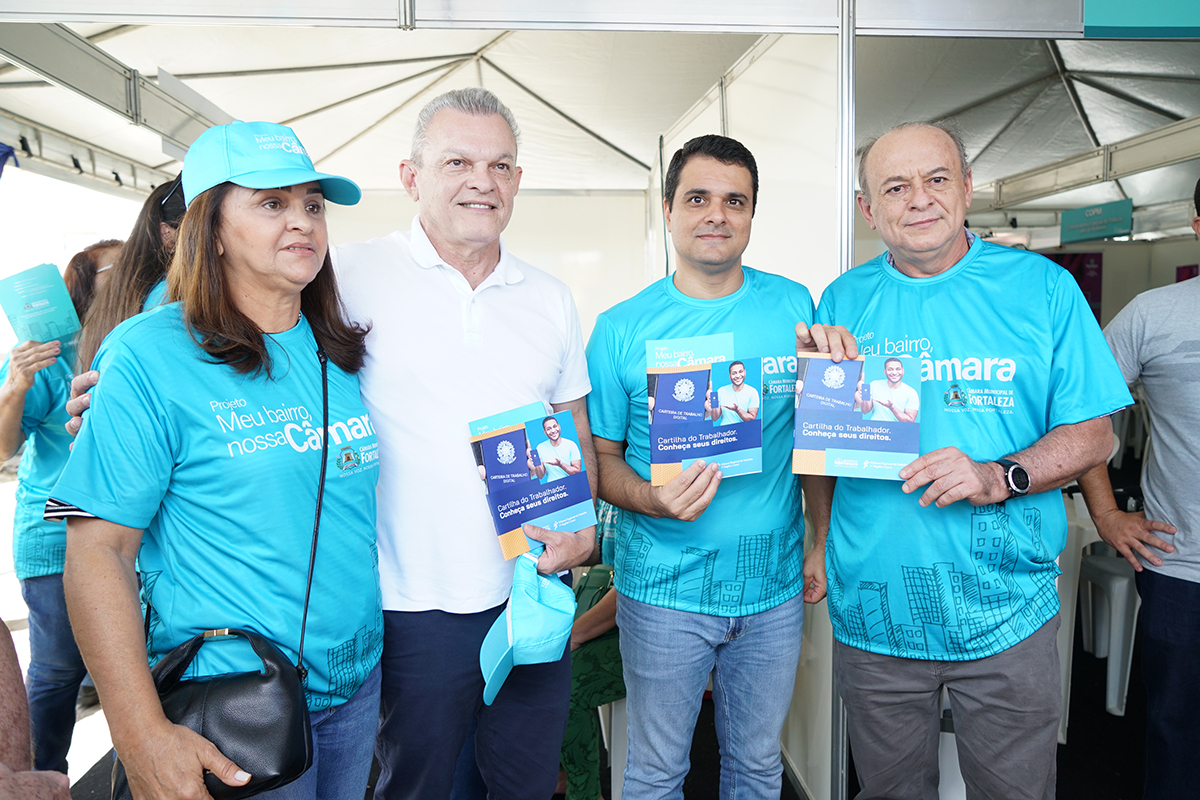 Uma mulher e três homens em pé segurando a cartilha do trabalhador