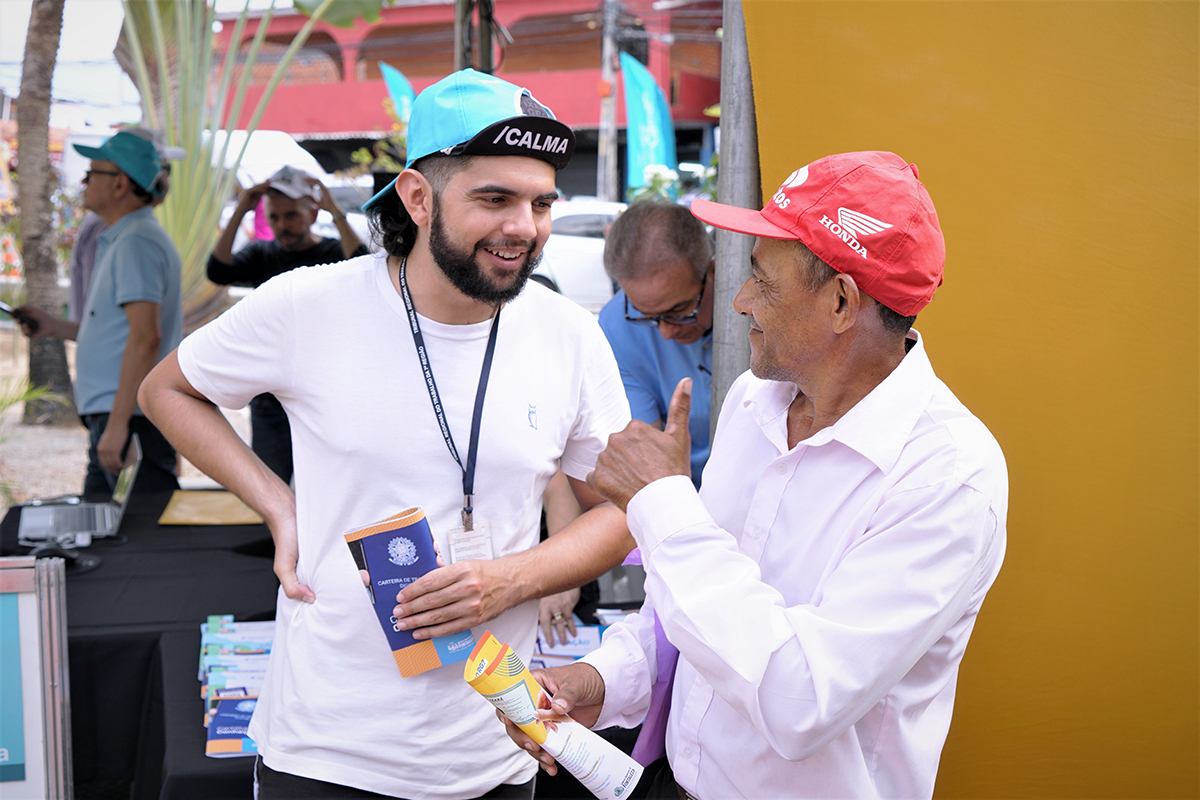 Estagiário da Justiça do Trabalho com a Cartilha do Trabalhador na mão tira dúvidas de um senhor