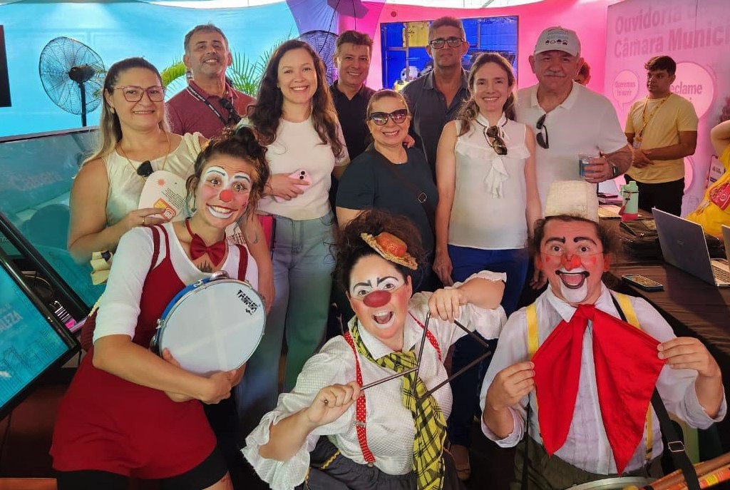 Foto Da esq. para direita: capitã da PM Tatiane Medeiros, servidores do TRT-7 e artistas do grupo. Eles estão sorridentes e os três artistas estão pintados de palhaços