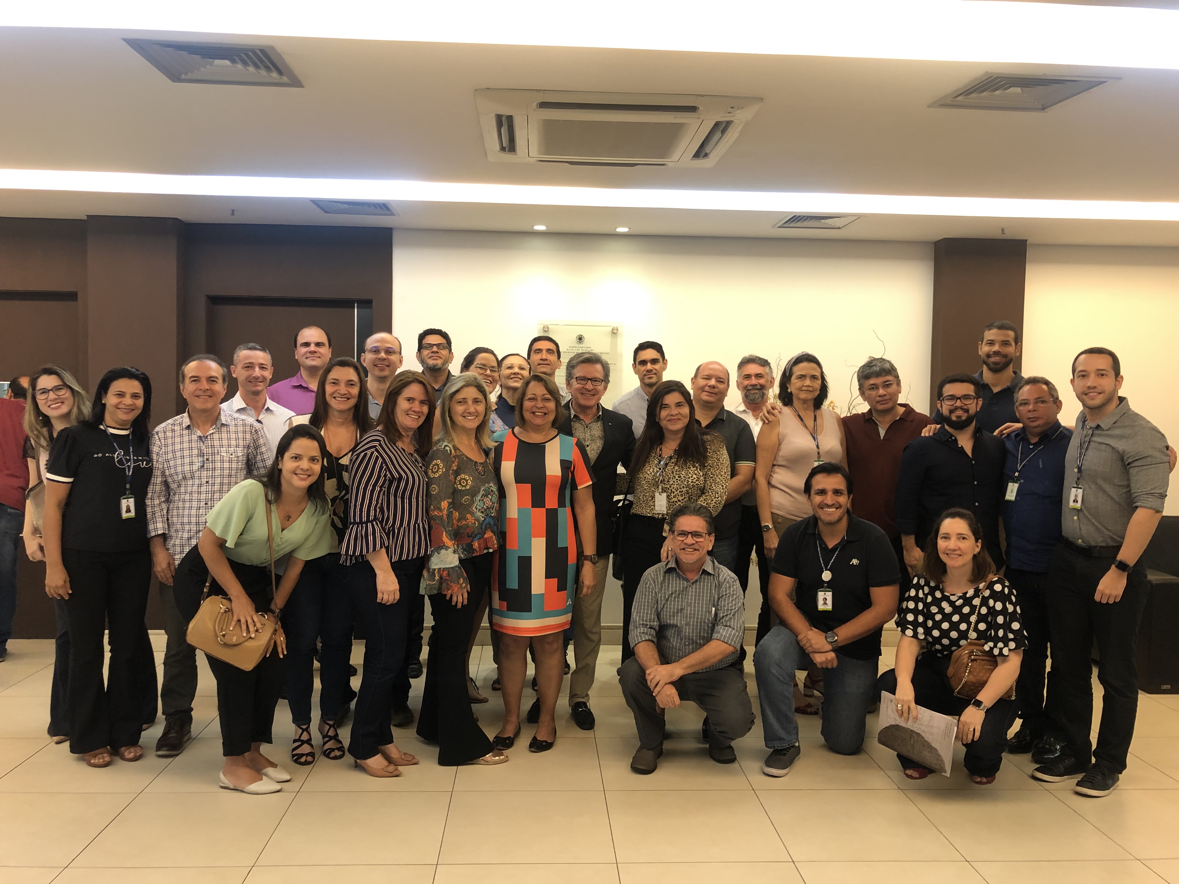 Foto do Encontro dos Oficiais do TRT-CE em novembro 2019. Estão todos em pé, sorridentes e no hall da Escola Judicial