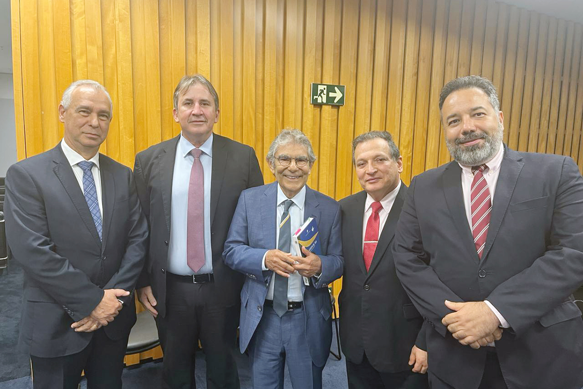 Cinco homens de paletó em pé no auditório