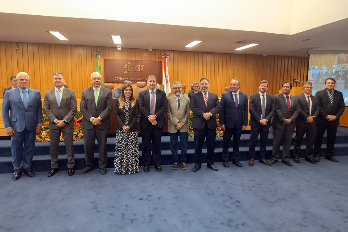 Membros da nova diretoria em pé lado a lado posando pra foto no auditório