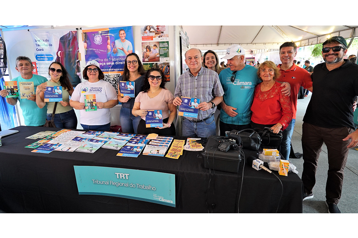 servidores e magistrados no estande do TRT-7 segurando cartilhas educativas para distribuição