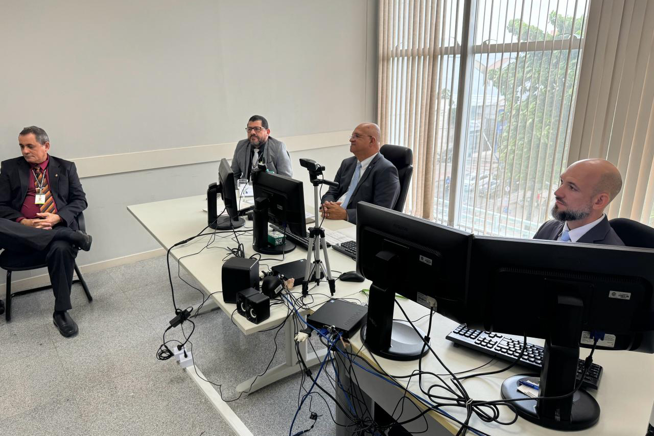 quatro homens sentados em mesa na frente de computadores