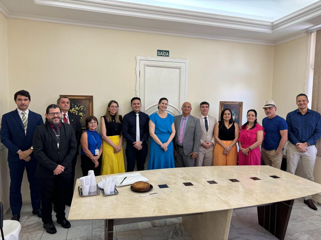 Várias pessoas posam pra foto em frente a uma mesa