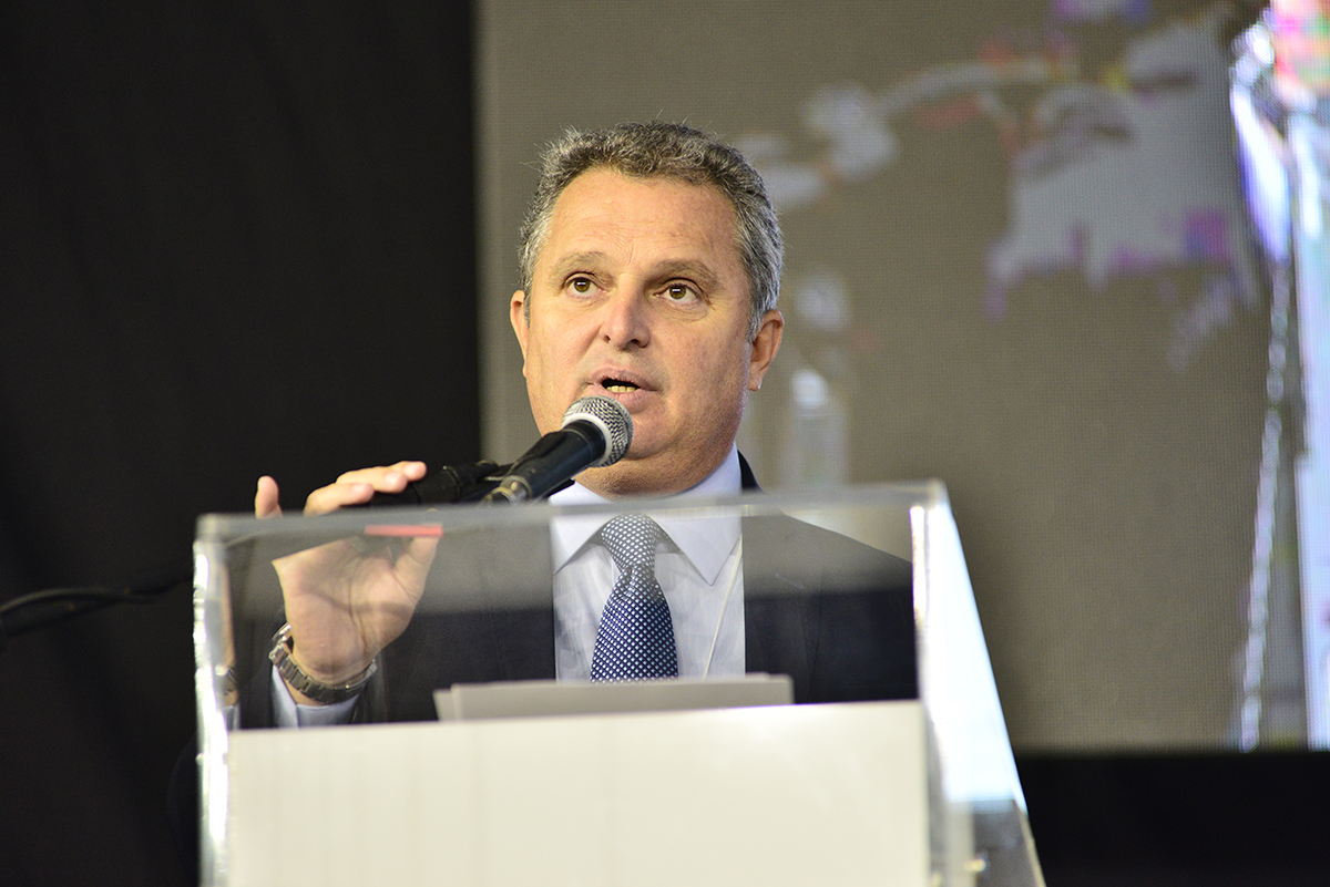 homem de paletó fala ao microfone na tribuna do evento