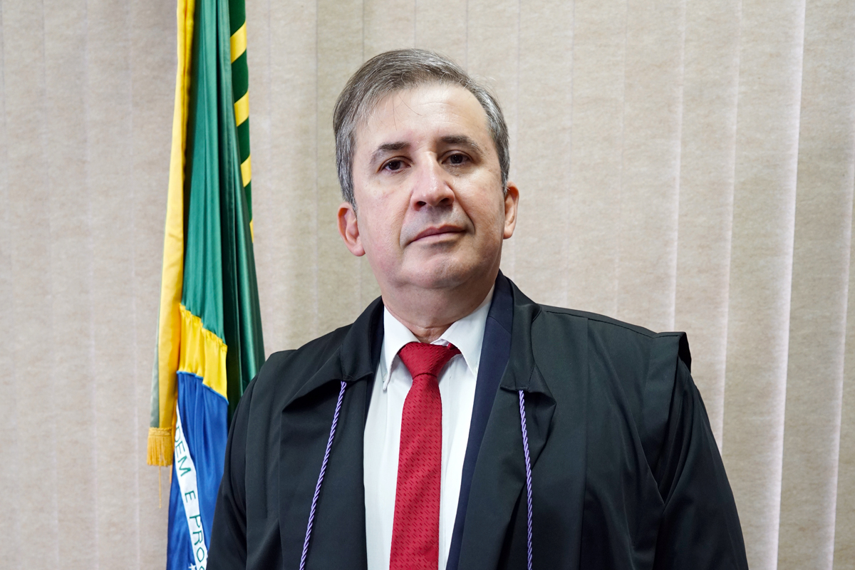 homem de terno posa na frente de uma bandeira