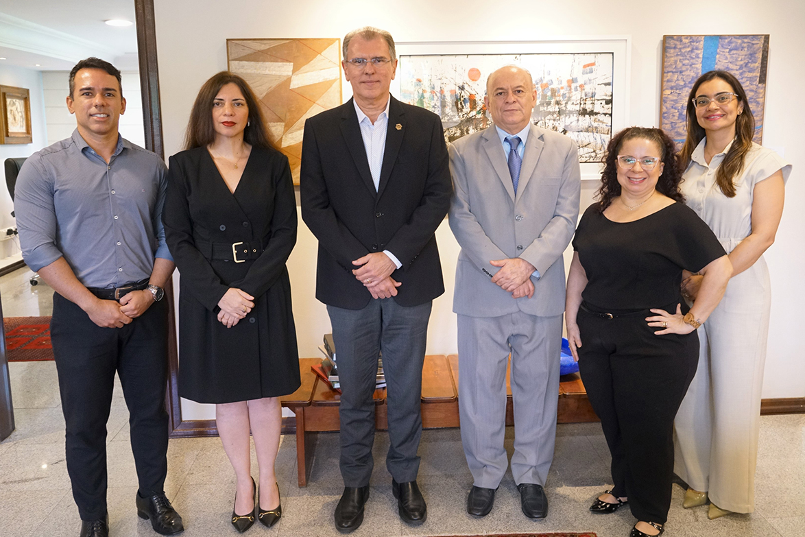 três homens e três mulheres em pé posam pra foto em uma sala com várias obras de arte na parede