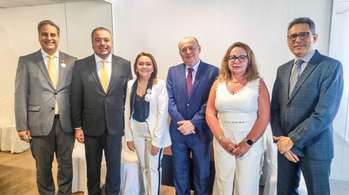 Quatro homens de paletó e duas mulheres de blazer posam pra foto numa sala