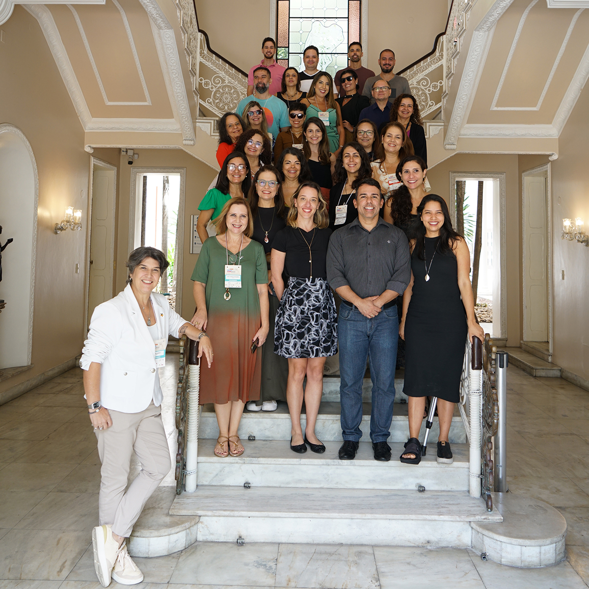 Cerca de 30 pessoas em pé numa escadaria clássica de uma casa