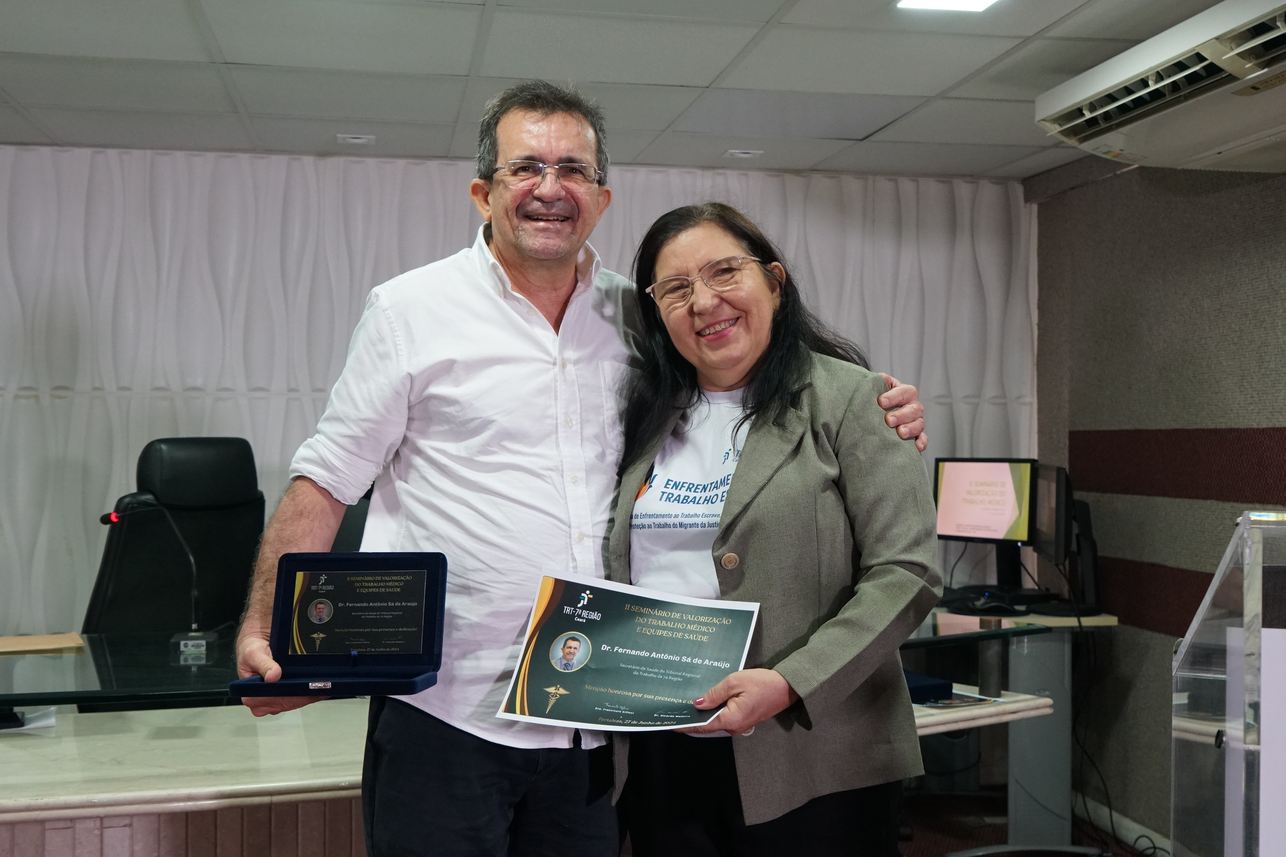 Foto do Secretário de Saúde do TRT-7 Fernando Antônio Sá e a médica Francineti Giffoni. Ambos estão sorridentes e estão segurando placa e certificado de participação