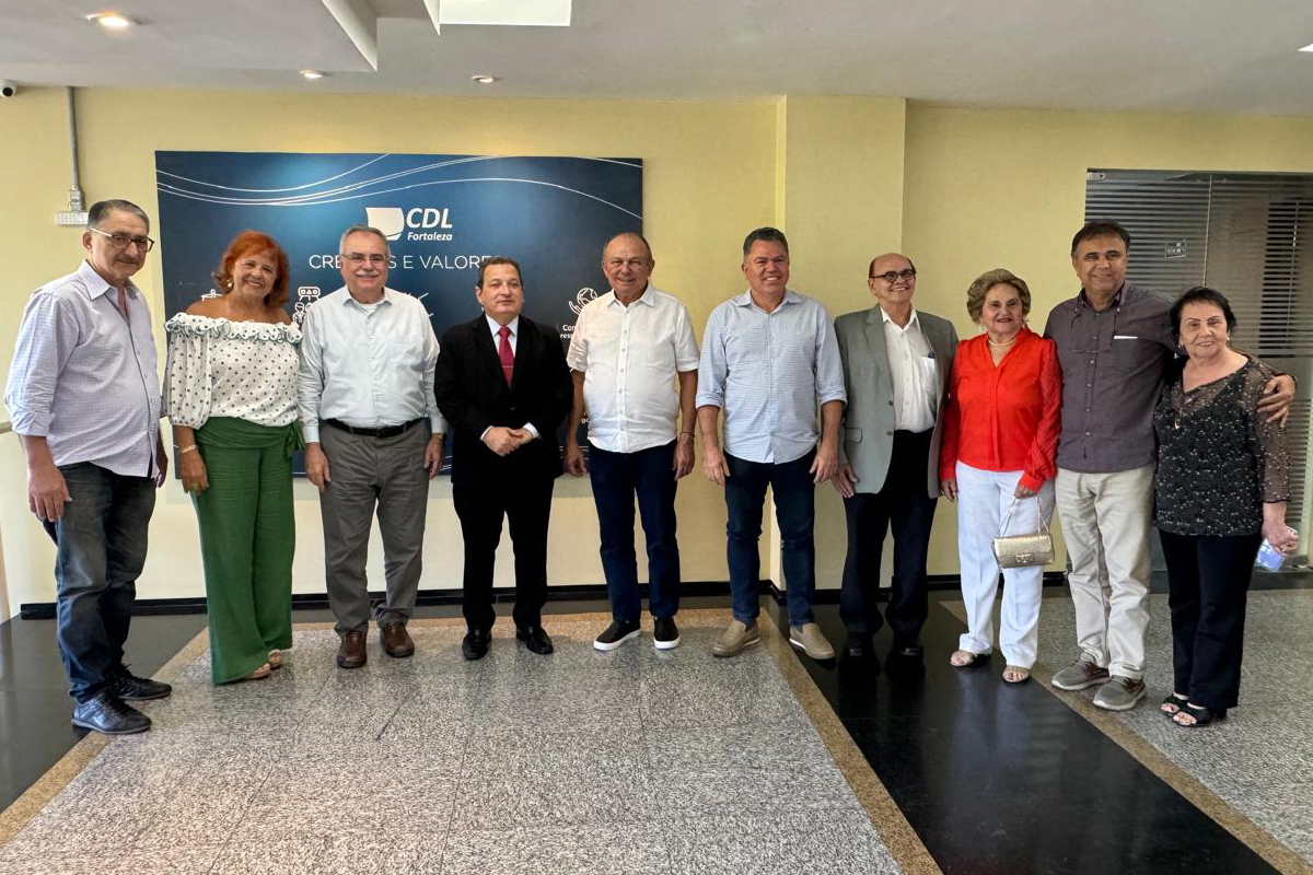 sete homens e três mulheres em pé numa sala de parede amarela na frente de um painel azul com o letreiro CDL Fortaleza