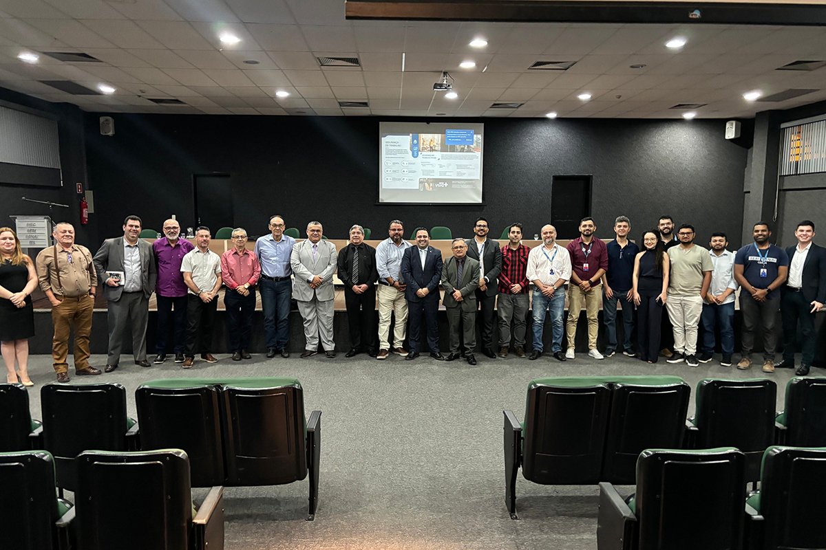 dezenas de pessoas em pé posam pra foto em um auditório