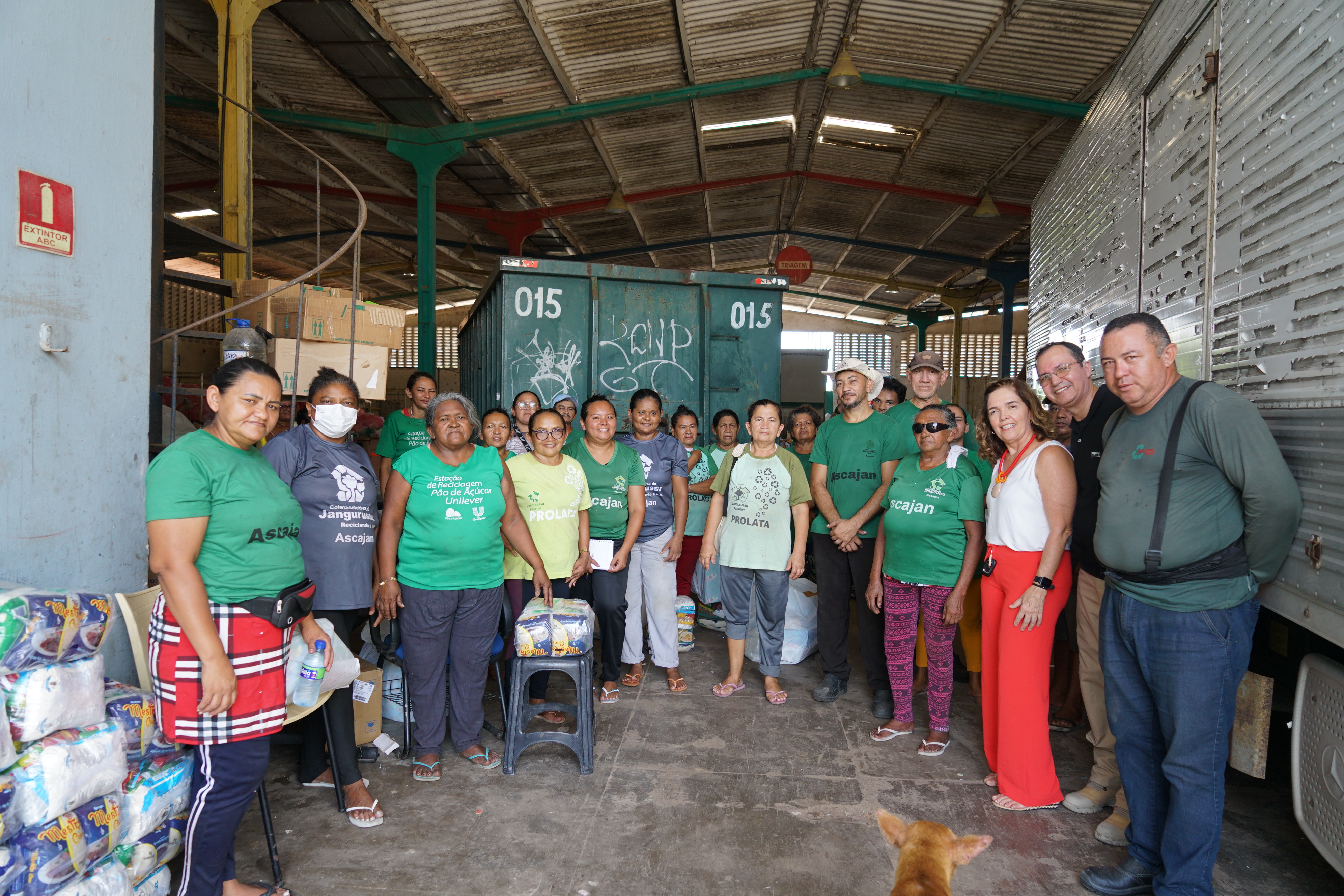 Foto dos catadores junto com servidores do TRT. Eles estão lado a lado, sorridentes e os catadores vestem blusa verde com o nome da Associação