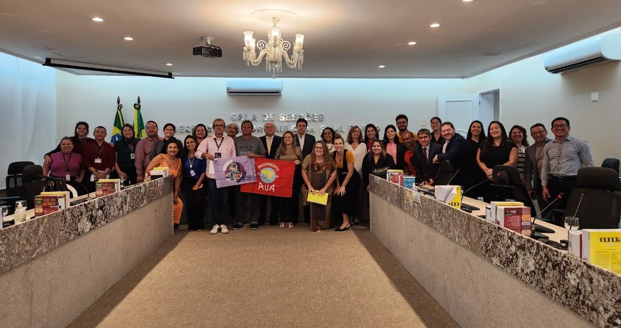 Foto de todos os participantes na sala de sessão do Pleno do TRT-CE. Eles estão posando para foto, segurando bandeiras do Movimento de Rua e são quase 30 pessoas. 
