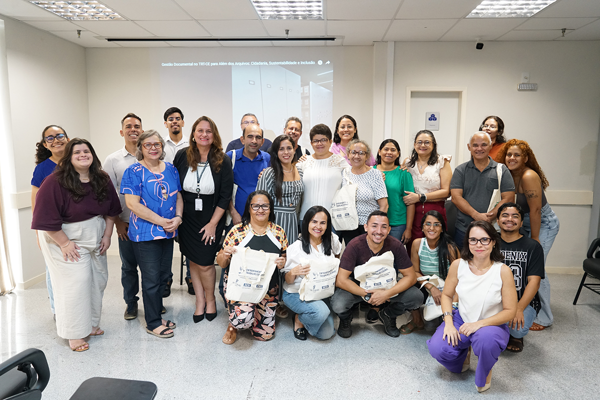 Dezenas de pessoas em pé e sentadas posam para foto exibindo os kits presenteados