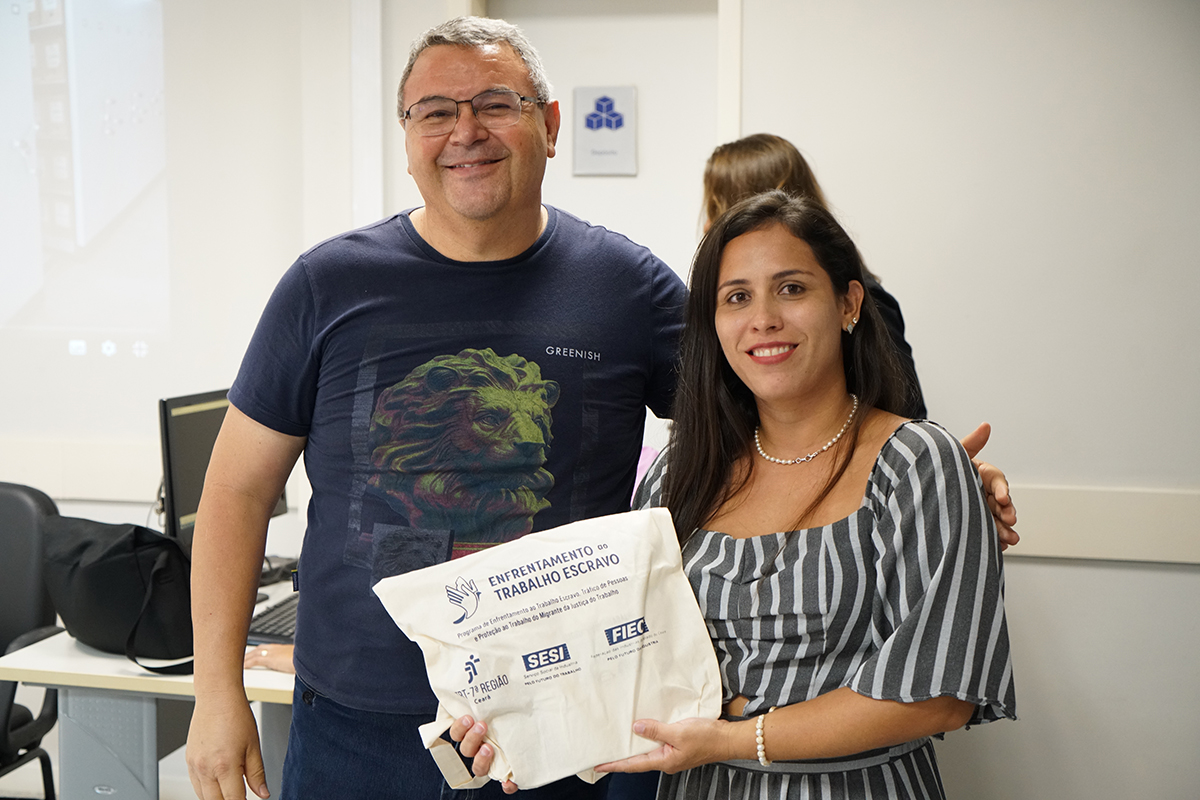 Homem ao lado de uma mulher, que exibe um kit de presente