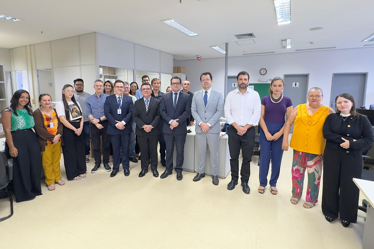  Várias pessoas em pé posam pra foto na secretaria da vara