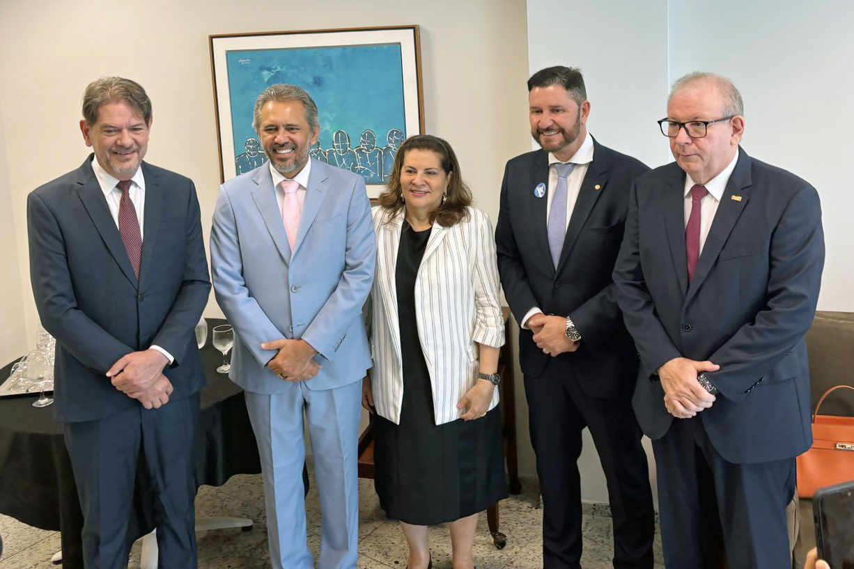 Quatro homens de terno e uma mulher de blazer no meio