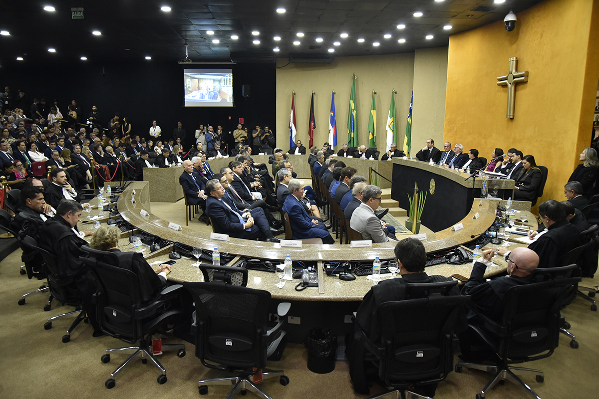 foto do plenário lotado de pessoas com a mesa diretora no canto esquerdo, ao lado de uma parede com bandeiras e outra com uma grande cruz