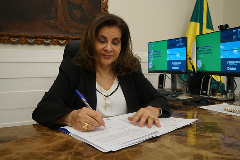 Foto da desa. Fernanda Uchoa assinando um documento em sua mesa na Presidência
