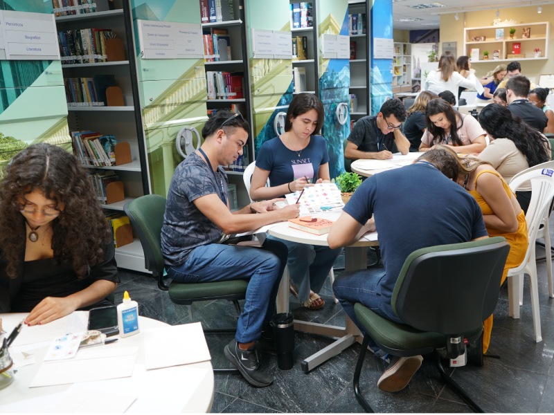 Foto dos estagiários escrevendo cartas na biblioteca