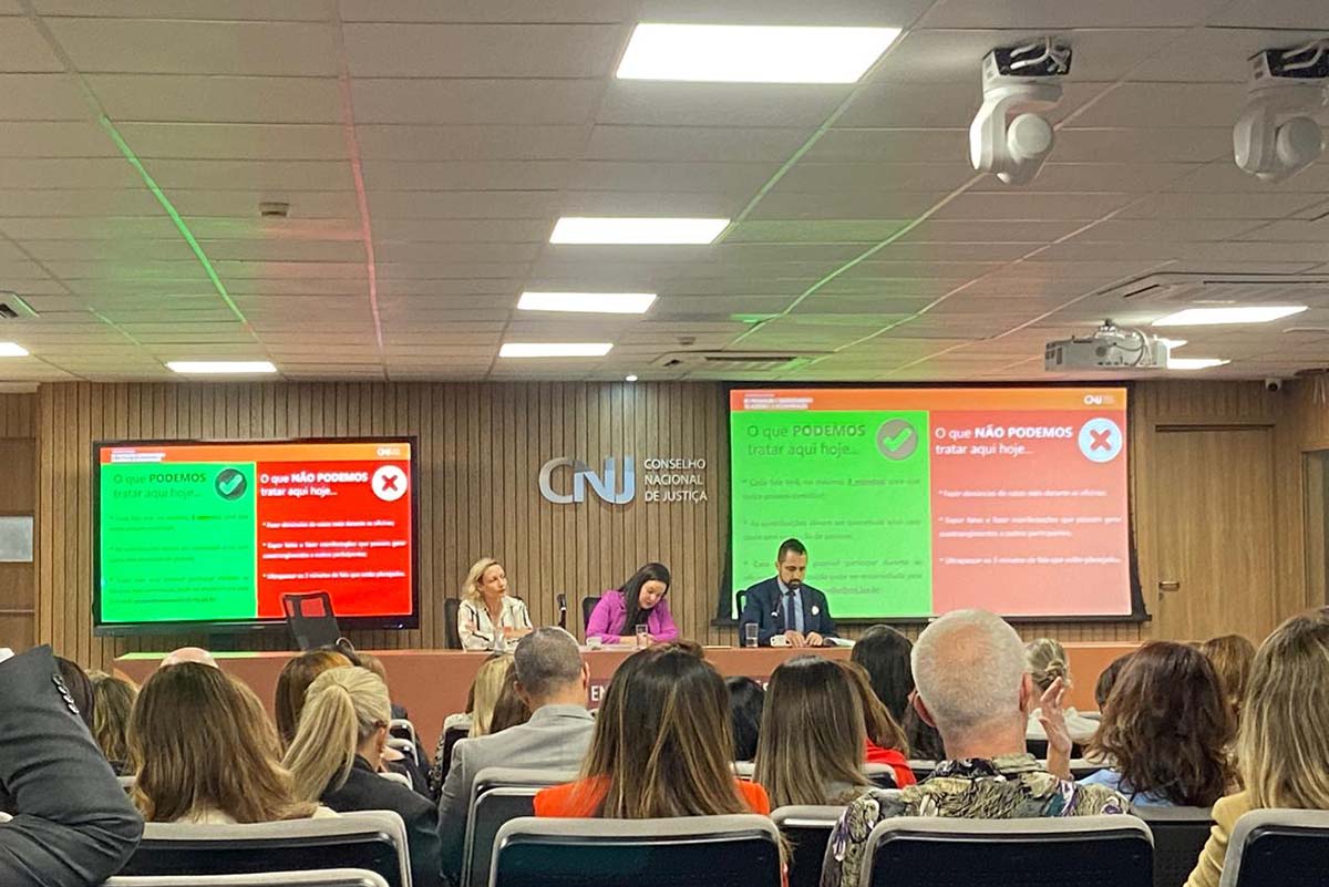 Uma foto de ambiente interno mostra uma mesa de painel com três participantes sentados, de frente para um auditório. O público, de costas para a câmera, preenche as cadeiras. Ao fundo, três grandes telas exibem o tema da discussão em caixas de texto nas cores verde ("O QUE PODEMOS tratar aqui hoje...") e vermelho ("O QUE NÃO PODEMOS tratar aqui hoje..."), focando nas regras e escopo do debate. O logotipo do CNJ está centralizado no painel de madeira.