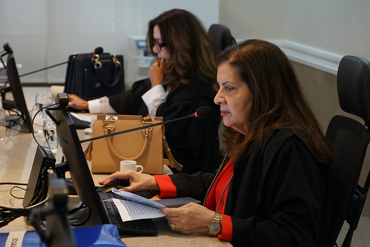 Foto da desa. Fernanda Uchôa lendo seu discurso. Ela está sentada e usa paletó preto e blusa vermelha