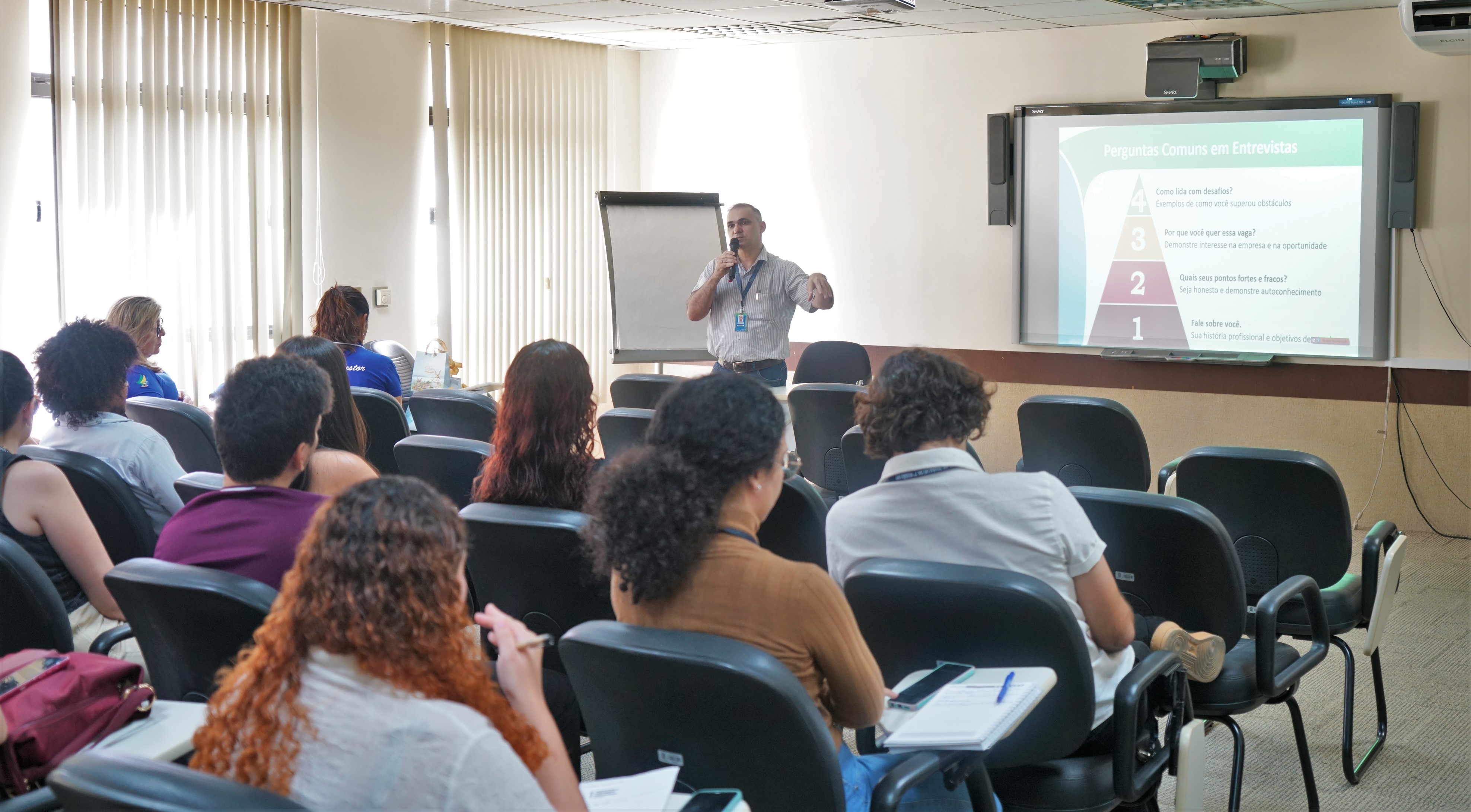 Foto dos estagiários sentados na sala de treinamento assistindo à palestra do gerente do Sine Idt