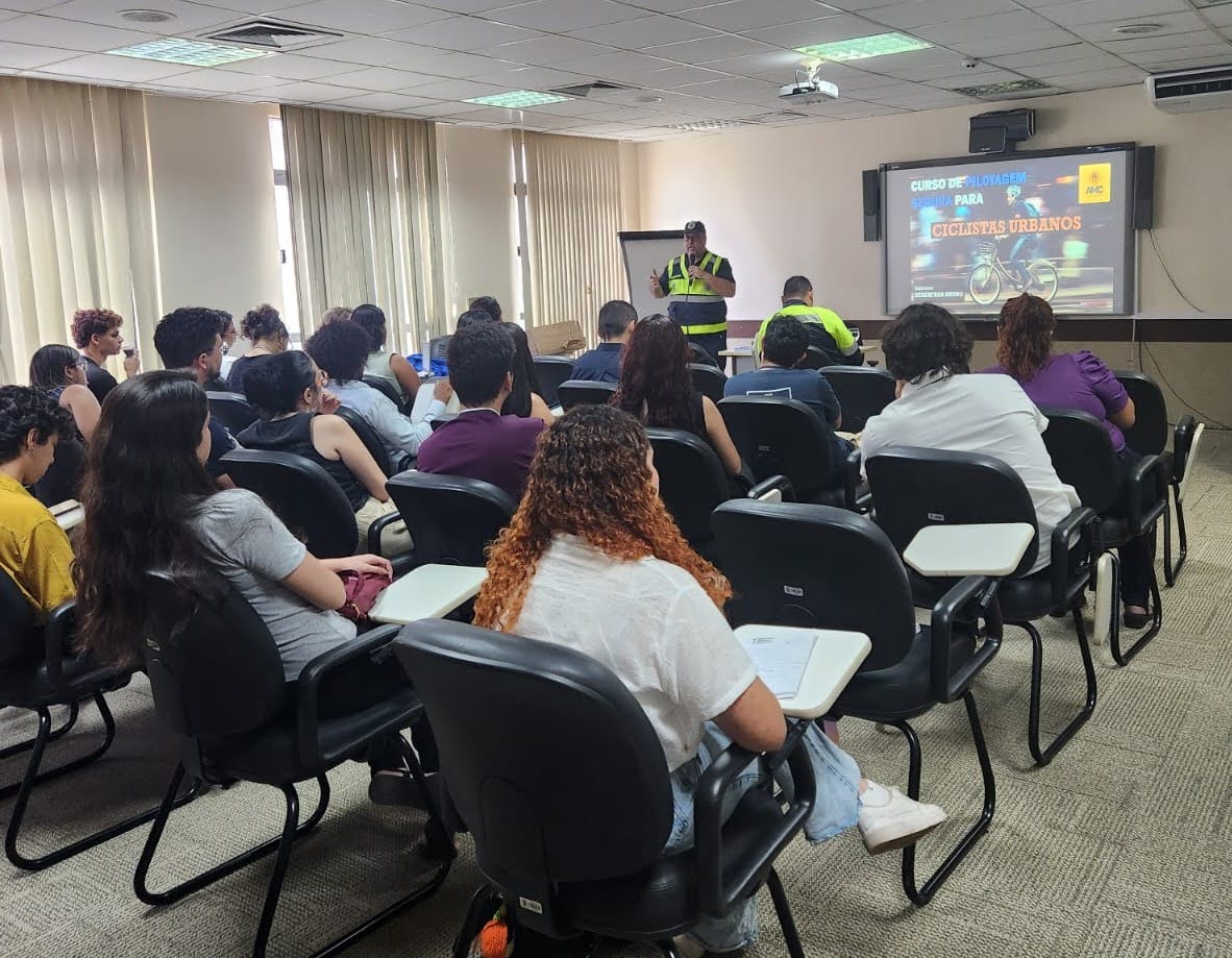 Foto dos estagiários sentados na sala de treinamento assistindo à palestra dos instrutores da AMC