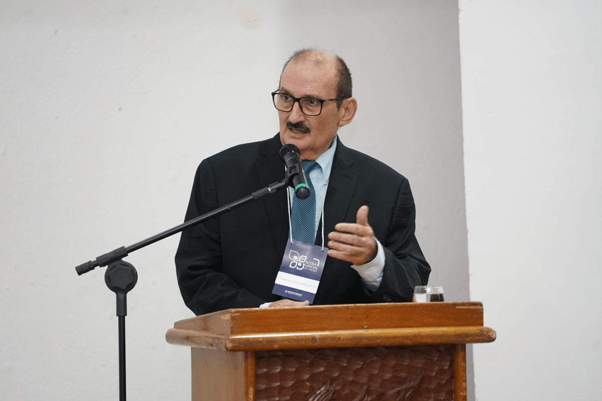 Card horizontal com fundo azul-marinho e grafismos geométricos em amarelo e azul claro. À esquerda, em uma moldura circular, a foto em preto e branco do Desembargador Franzé Gomes, sorridente e vestindo terno e gravata. À direita, o texto em branco e amarelo destaca seu nome e o título da palestra: "Inovações na Execução Trabalhista", com logomarcas institucionais nas bordas superior e inferior.